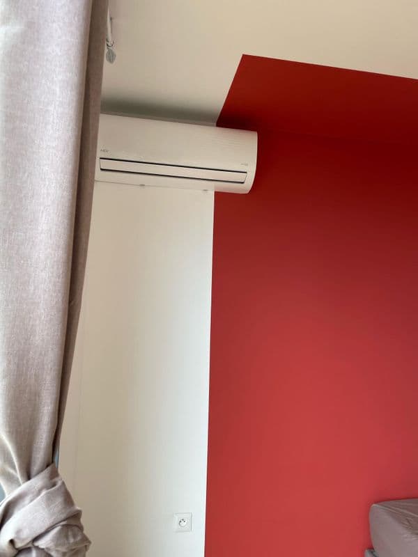Climatiseur mural intérieur installé dans une chambre avec mur rouge